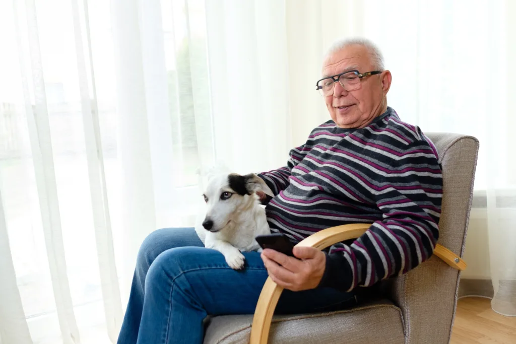 older man looking at his phone with dog on his lap